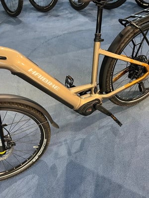 Detail eines Haibike E-Bikes mit goldenem Rahmen und schwarzen Rädern auf blauem Teppich.