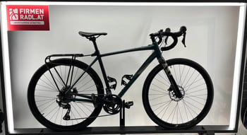 Ein grünes Fahrrad mit Gepäckträger und Firmenlogo auf rotem Schild.