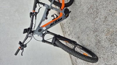 Graues KTM E-Bike mit orangefarbenen Details auf gepflastertem Untergrund. Graues KTM E-Bike mit orangefarbenen Details auf gepflastertem Untergrund.