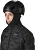 Frau in schwarzer Jacke und Helm mit Patagonia-Logo, isoliert auf weißem Hintergrund.