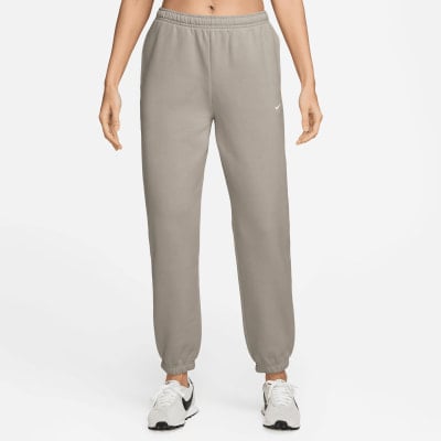 Graue Nike Jogginghose für Damen mit Logo am Oberschenkel und weißen Sneakern.
