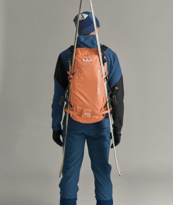Ein Mann in Skibekleidung mit Rucksack und Skiern auf dem Rücken. Ein Mann in Skibekleidung mit Rucksack und Skiern auf dem Rücken.