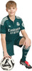 Junge im grünen Fußballtrikot mit Ball am Fuß.