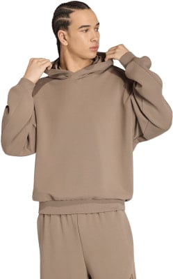 Ein Mann in einem braunen Hoodie und einer Jogginghose mit Adidas-Logo. Ein Mann in einem braunen Hoodie und einer Jogginghose mit Adidas-Logo.