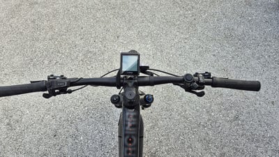 Lenker eines E-Bikes mit Display und Griffen auf Asphalt. Lenker eines E-Bikes mit Display und Griffen auf Asphalt.