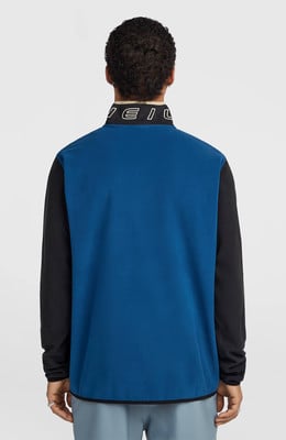 Rückansicht eines Mannes in einer blauen Fleecejacke mit schwarzen Ärmeln und Logo. Rückansicht eines Mannes in einer blauen Fleecejacke mit schwarzen Ärmeln und Logo.