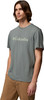 Ein Mann in einem grauen T-Shirt mit Columbia-Logo und brauner Hose.