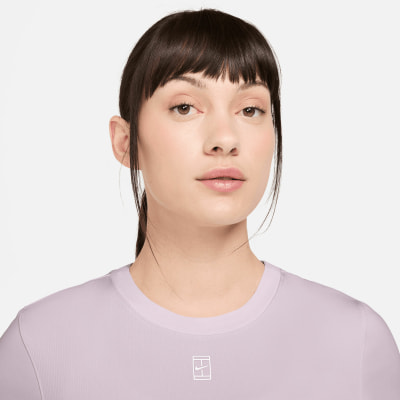Eine Frau mit dunklem Haar und heller Haut trägt ein lilafarbenes T-Shirt mit Logo. Eine Frau mit dunklem Haar und heller Haut trägt ein lilafarbenes T-Shirt mit Logo.