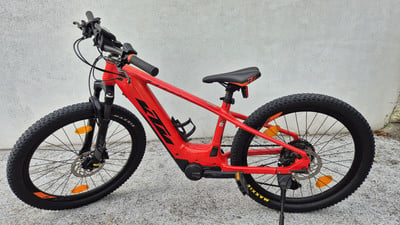 Ein rotes KTM Kinder-E-Bike mit dicken Reifen steht auf Schotter.