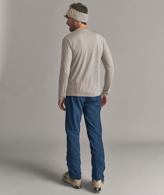 Ein Mann in Skihose und Mütze mit langen Ärmeln steht mit dem Rücken. Ein Mann in Skihose und Mütze mit langen Ärmeln steht mit dem Rücken.