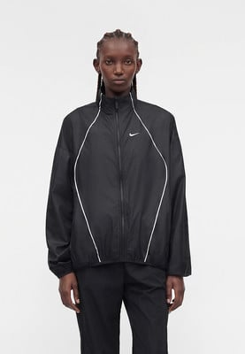 Női fekete Nike dzseki fehér részletekkel és logóval a mellkasán. Női fekete Nike dzseki fehér részletekkel és logóval a mellkasán.