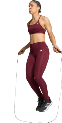 Eine Frau in dunkelroter Sportkleidung springt über ein Seil. Eine Frau in dunkelroter Sportkleidung springt über ein Seil.
