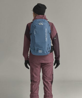 Eine Frau in Winterkleidung mit einem blauen Rucksack auf dem Rücken.