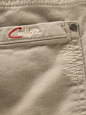Stoffdetail mit gesticktem Markenlogo in Rot und Beige. Stoffdetail mit gesticktem Markenlogo in Rot und Beige.