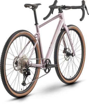 Ein rosafarbener Gravelbike-Rahmen mit braunen Reifen und schwarzen Komponenten. Ein rosafarbener Gravelbike-Rahmen mit braunen Reifen und schwarzen Komponenten.
