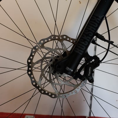 Detail des vorderen Scheibenbremssystems eines Mountainbikes mit RockShox-Aufschrift. Detail des vorderen Scheibenbremssystems eines Mountainbikes mit RockShox-Aufschrift.