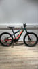Ein graues KTM E-Bike mit orangen Akzenten steht auf einem Holzboden.