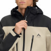 Ein Mann schließt eine beige Jacke mit schwarzen Details und Kapuze.