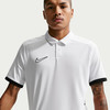 Mann in einem weißen Poloshirt mit schwarzem Nike-Logo und schwarzen Ärmelbündchen.