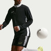 Fußballer im schwarzen Trikot und Shorts mit Ball am Fuß.