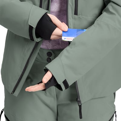 Eine Person in Skikleidung steckt eine Karte in eine Ärmeltasche.