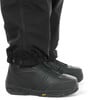 Schwarze Hose und Stiefel mit Gummisohle auf weißem Hintergrund.