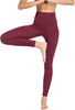 Eine Frau in burgunderfarbenen Leggings macht Yoga vor weißem Hintergrund.