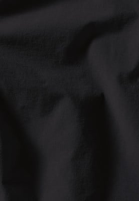 Schwarzer Stoff mit feiner Textur und Falten wirkt weich. Schwarzer Stoff mit feiner Textur und Falten wirkt weich.