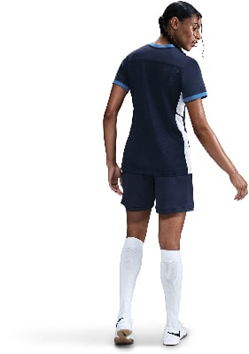 Eine Frau in einem dunkelblauen Sporttrikot und Shorts mit weißen Socken. Eine Frau in einem dunkelblauen Sporttrikot und Shorts mit weißen Socken.