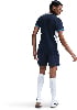 Eine Frau in einem dunkelblauen Sporttrikot und Shorts mit weißen Socken.