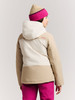 Mädchen in einer beigen Jacke mit Kapuze und pinker Hose.