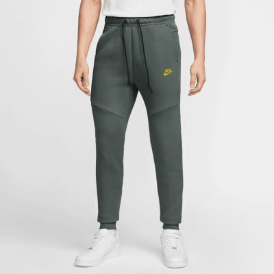 Herren-Jogginghose von Nike in Dunkelgrün mit gelbem Logo und weißen Turnschuhen. Herren-Jogginghose von Nike in Dunkelgrün mit gelbem Logo und weißen Turnschuhen.