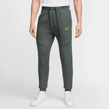 Herren-Jogginghose von Nike in Dunkelgrün mit gelbem Logo und weißen Turnschuhen.