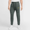 Herren-Jogginghose von Nike in Dunkelgrün mit gelbem Logo und weißen Turnschuhen.
