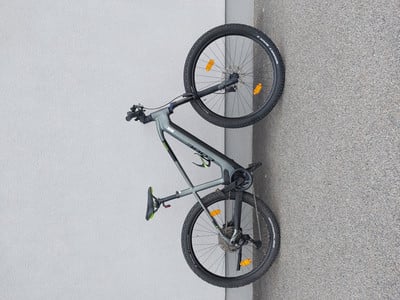 Graues Mountainbike, das an einer weißen Wand lehnt, Vorder- und Hinterrad sichtbar.