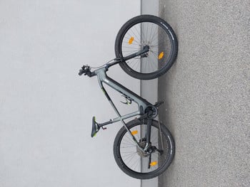 Graues Mountainbike, das an einer weißen Wand lehnt, Vorder- und Hinterrad sichtbar.