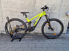 Ein gelbes E-Mountainbike steht auf einem Ständer an einer Wand.