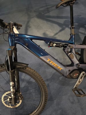 Ein blaues Trek E-Mountainbike mit Federung und Scheibenbremsen.