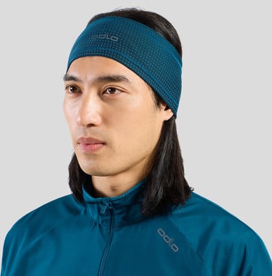 Ein Mann trägt ein blaues Stirnband und eine Jacke mit Odlo-Logo.