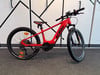 Ein rotes KTM E-Bike mit Federung und schwarzen Rädern auf einem Ständer.