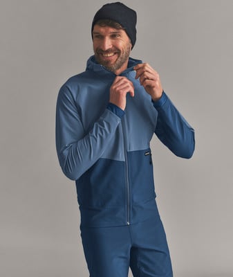 Ein Mann in einer blauen Jacke und Mütze verstellt den Reißverschluss.