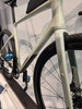 Ein hellgraues Gravelbike der Marke Cube mit blauen Pedalen und schwarzen Reifen.