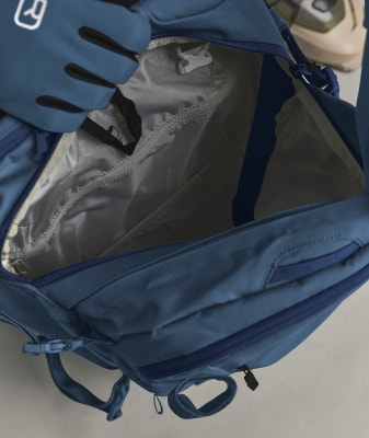 Blaue Tasche mit offenem Fach und Handschuh darin.