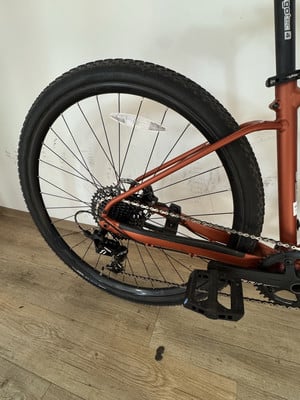 Das Hinterrad eines orangefarbenen Fahrrads mit Kette und Pedal auf Holzboden. Das Hinterrad eines orangefarbenen Fahrrads mit Kette und Pedal auf Holzboden.