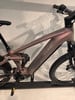 Ein rosafarbenes Cube E-Bike mit Federung und robustem Rahmen.