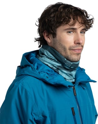Ein Mann in einer blauen Jacke mit einem bedruckten Schlauchtuch und lockigen Haaren. Ein Mann in einer blauen Jacke mit einem bedruckten Schlauchtuch und lockigen Haaren.
