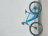 Ein blaues E-Mountainbike mit schwarzen Rädern steht an einer Wand.