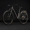 Schwarzes Mountainbike mit Schutzblechen und Gepäckträger vor dunklem Hintergrund.