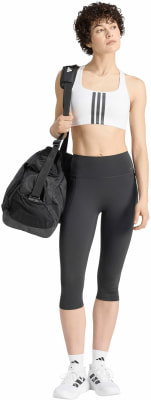 Eine Frau im weißen Sport-BH und schwarzer Leggings mit einer Tasche über der Schulter. Eine Frau im weißen Sport-BH und schwarzer Leggings mit einer Tasche über der Schulter.