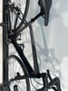 Ein schwarzes Rennrad hängt an einem Ständer, Detail von Rahmen und Rädern.